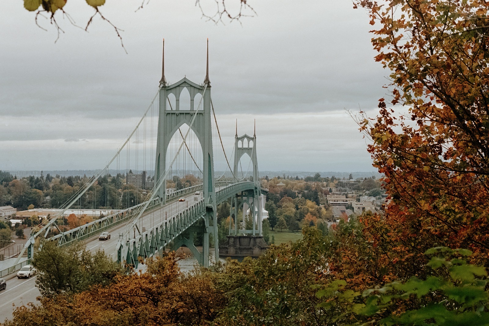 The St. Johns Bridge’s Gothic-style towers rise above the Willamette River, framed by lush green trees.