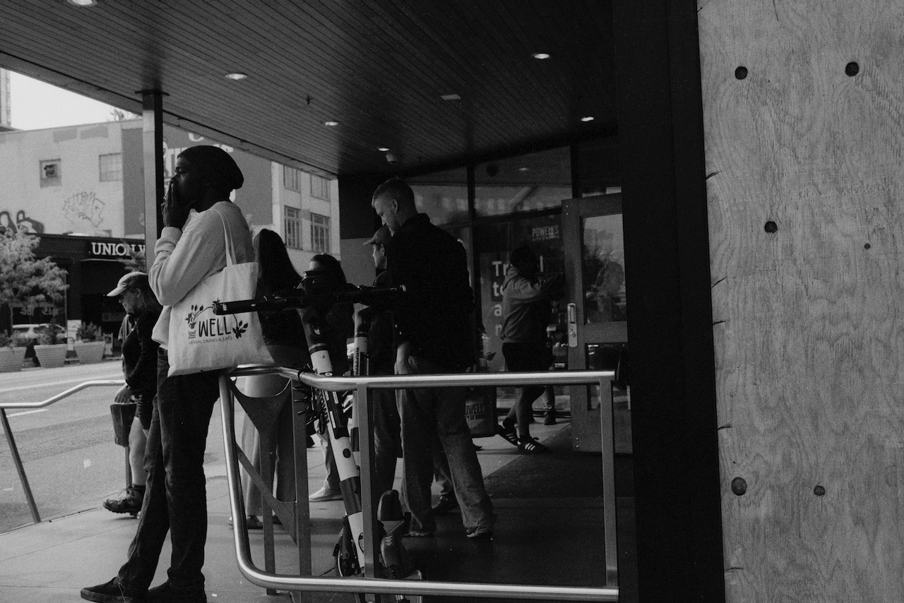 Exterior of Powell's City of Books in Portland, Oregon. A man with a tote bag stands on the left smoking a cigarette.