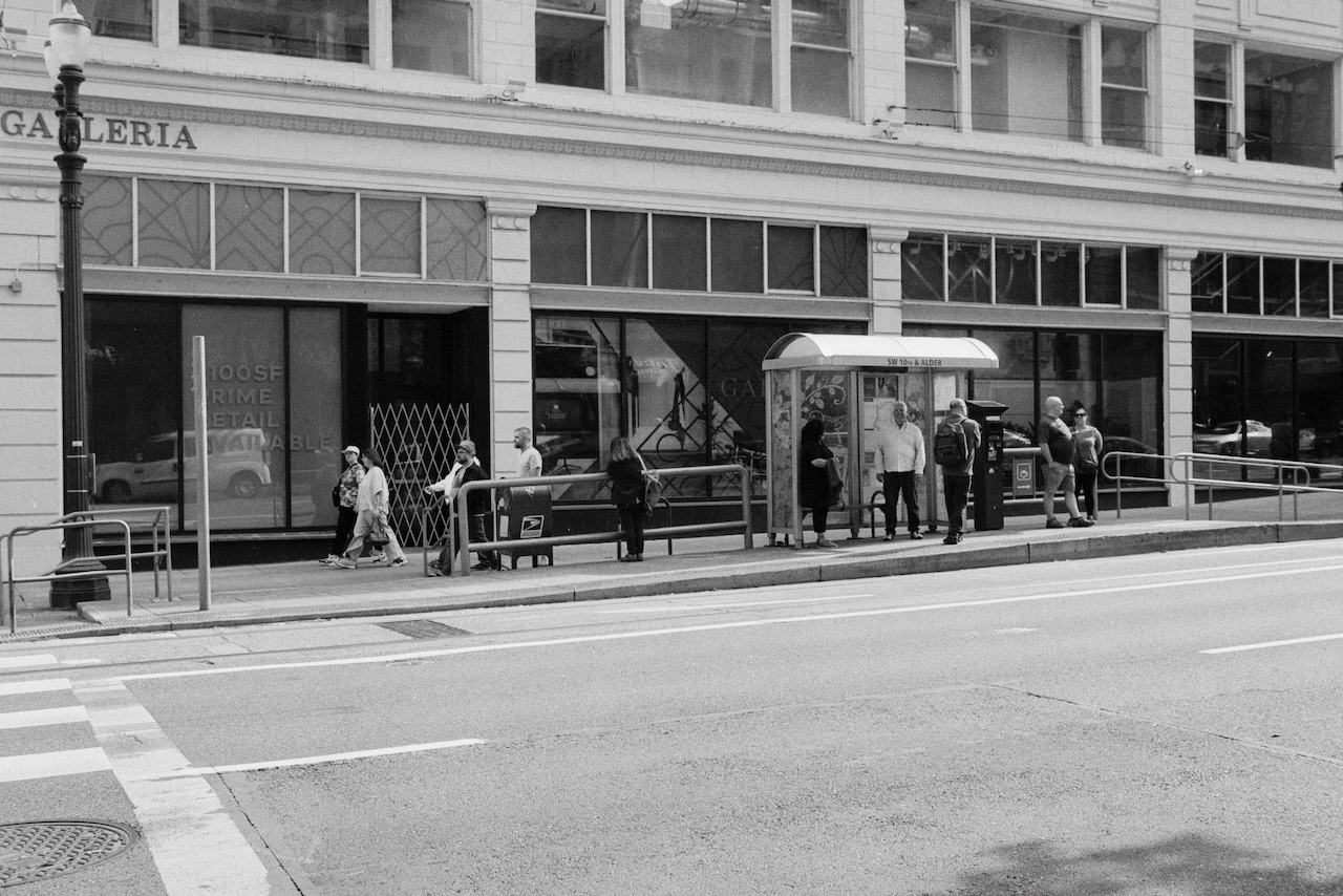 Black-and-white photo of people waiting at a train stop in Portland, Oregon.